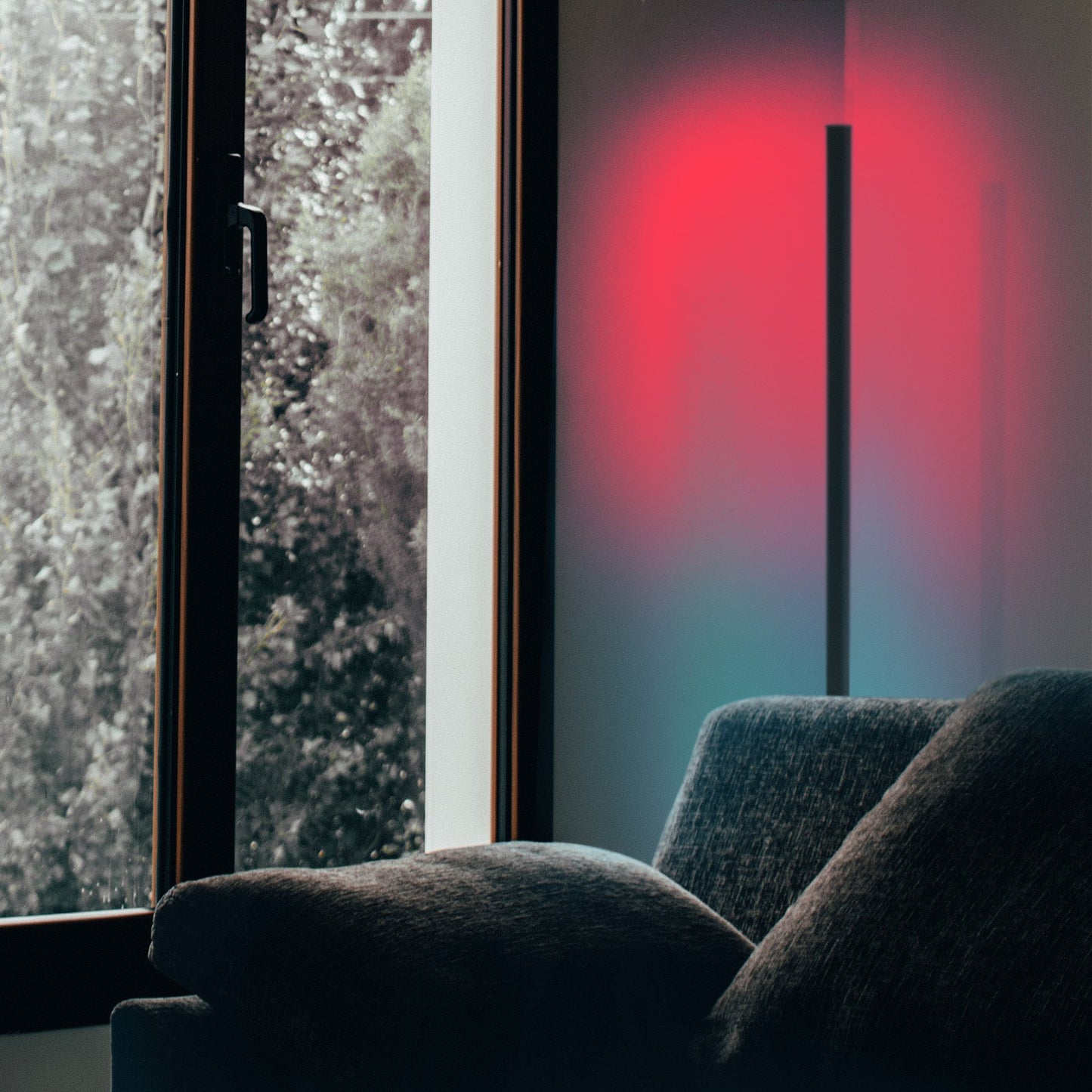 Sofa in a room with a large window showing a snowy outdoor scene with cornor lamp.