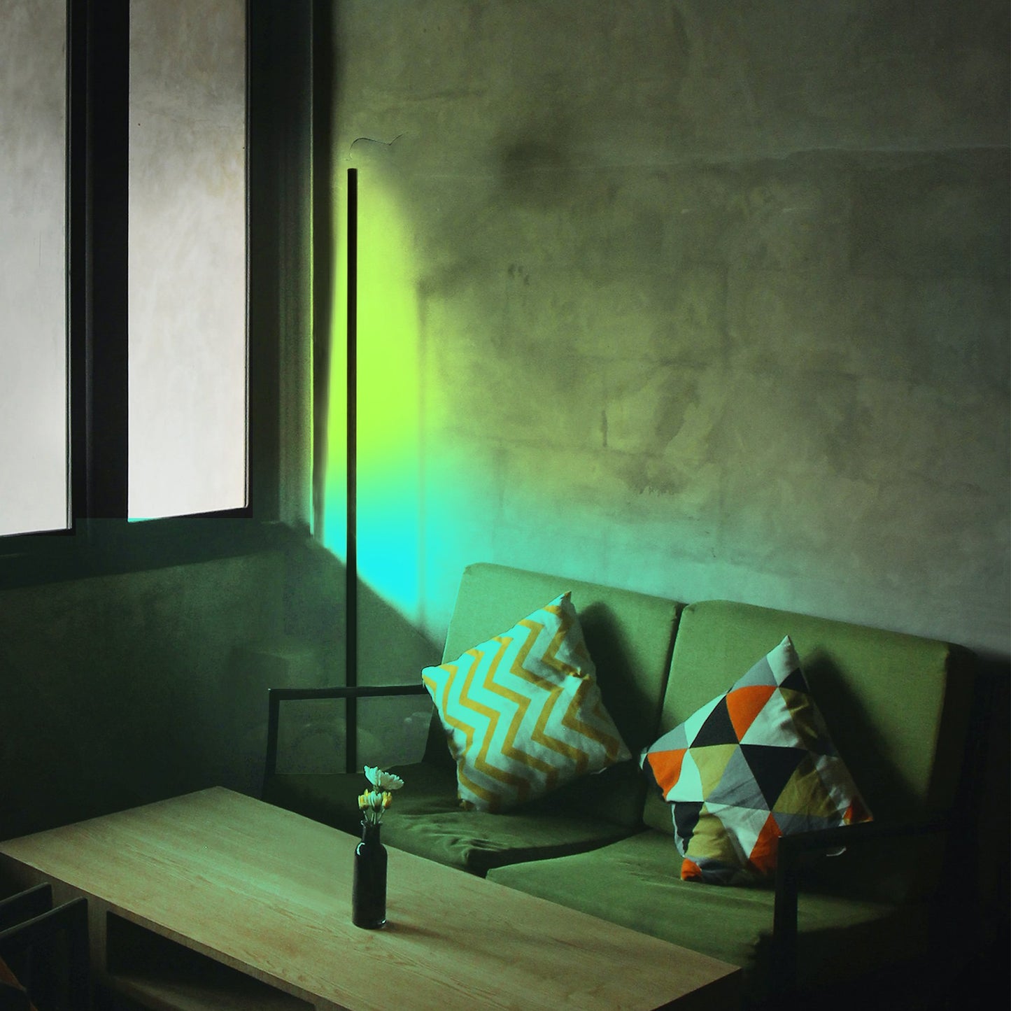Green sofa with colorful cushions in a dimly lit room with a lamp casting a green glow with cornor lamp.