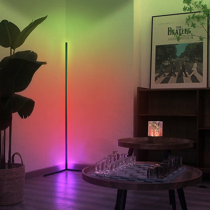 Modern interior with a standing cornor lamp casting colorful light, a Beatles poster, and a small table with glasses.